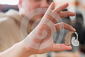 A young man puts on a hearing aid. Portable sound amplifier for the deaf and hearing impaired