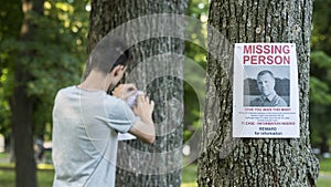 A young man puts up ads for a missing person in the park