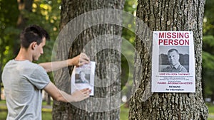 A young man puts up ads for a missing person in the park