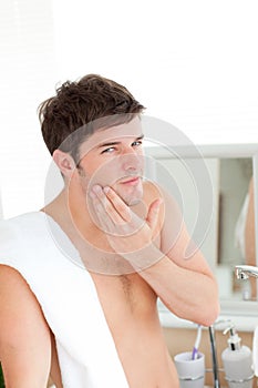 Young man putting aftershave in the bathroom