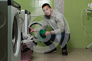 Young Man Putting A Cloth Into Washing Machine