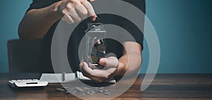 Young man putting coin in to jar, saving, charity, family finance plan concept, fundraising, superannuation, investment