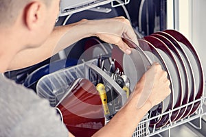 Young man putting a dishwashing machine