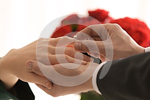 Young man putting engagement ring on fiancee's finger