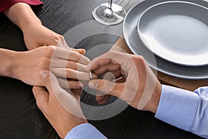 Young man putting engagement ring on fiancee's finger, closeup