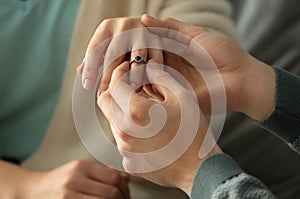 Young man putting engagement ring on fiancee's finger, closeup