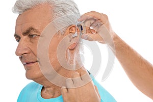 Young man putting hearing aid in father`s ear