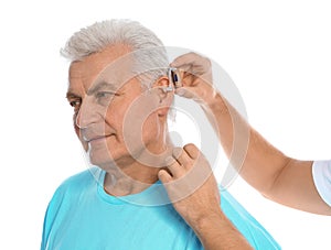 Young man putting hearing aid in father`s ear