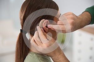 Young man putting hearing aid in woman`s ear