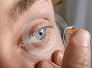 Young man putting lens in his eye, closeup