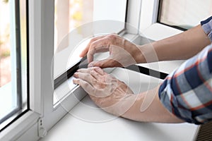 Young man putting sealing foam tape