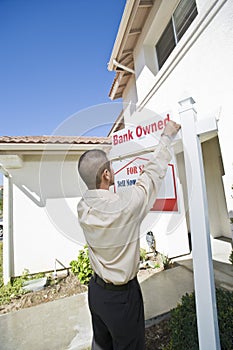 Young Man Putting Up 'For Sale Notice'