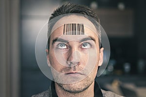 Young man with a qr code on his forehead. A man with a stupid expression looks at his qr code on his head. The concept of chipping