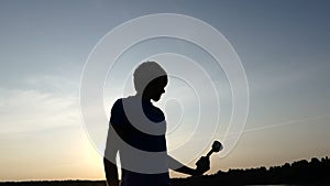 Young man raises up his champion bowl and smiles at sunset