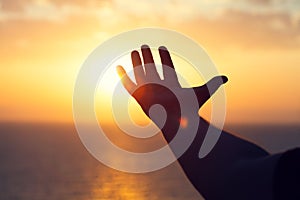 Young man raising hands praying at sunset or sunrise light