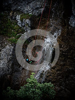 Young man rappelling abseiling from vertical rock, adventure sport at Stuiben waterfall in Reutte Tyrol Austria alps