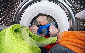 Young man Reaching Inside a washing machine or dryer doing laundry View from the inside