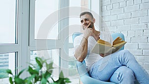 Young man read book sitting on balcony in modern apartment