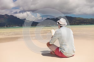 Young man reading a book on the beach