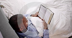 Young Man Reading Book On Bed
