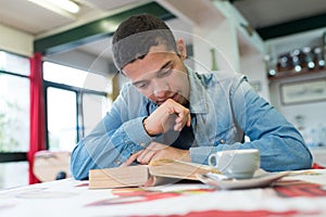 young man reading book in cafe