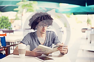 Young man reading book in cafe