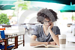 Young man reading book in cafe