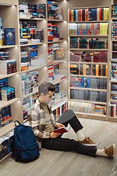 Young man reading a book in a cozy bookstore setting