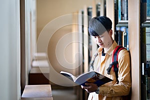 A young man is reading a book in a library