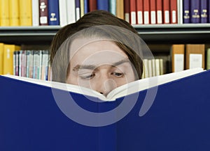 Young Man Reading Book In Library