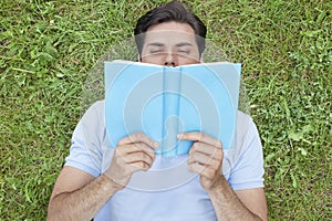 Young man reading book while lying on grass