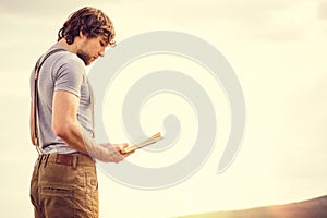 Young Man reading book outdoor with scandinavian lake on background