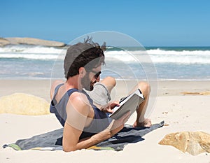 Young man reading book on secluded beach photo