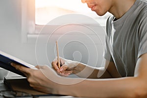 Young man reading book and writing in note at work desk in free time from working at home, Knowledge and learning concept.