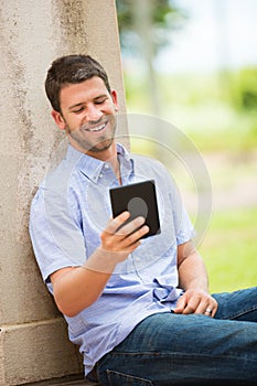 Young man reading E-book outside