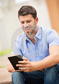 Young man reading E-book outside