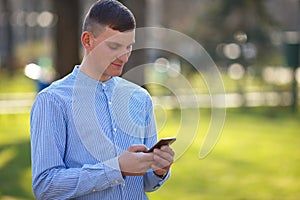 Young man reading message on smart phone outdoors. Conversation,