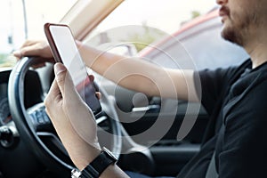 Young man reading messages holding a cell phone while driving. Dangerous behavior, accident risk