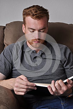 Young Man Reading in a Plush Chair