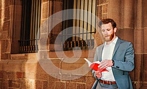 Young man reading red book on street in New York City