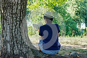 Young man reading under a tree in summer