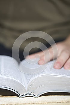 A young man reads the Bible, laying it on a wooden plank of boards.