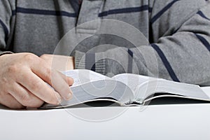 A young man reads the Bible with a silver slice sitting at the table.