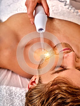 Young man receiving electric facial massage.