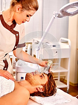 Young man receiving electric facial massage photo