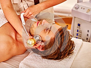 Young man receiving electric facial massage. photo
