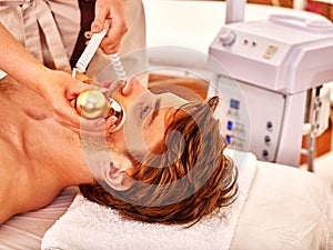 Young man receiving electric facial massage. photo