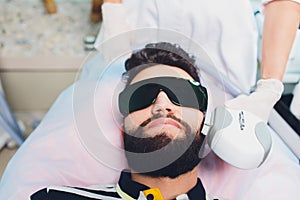 Young Man Receiving Laser Hair Removal Treatment At Beauty Center.