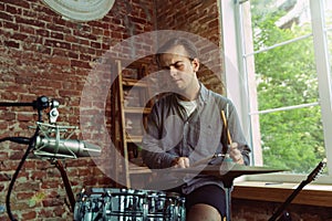 Young man recording music, playing drums and singing at home