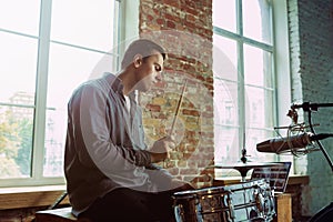 Young man recording music, playing drums and singing at home